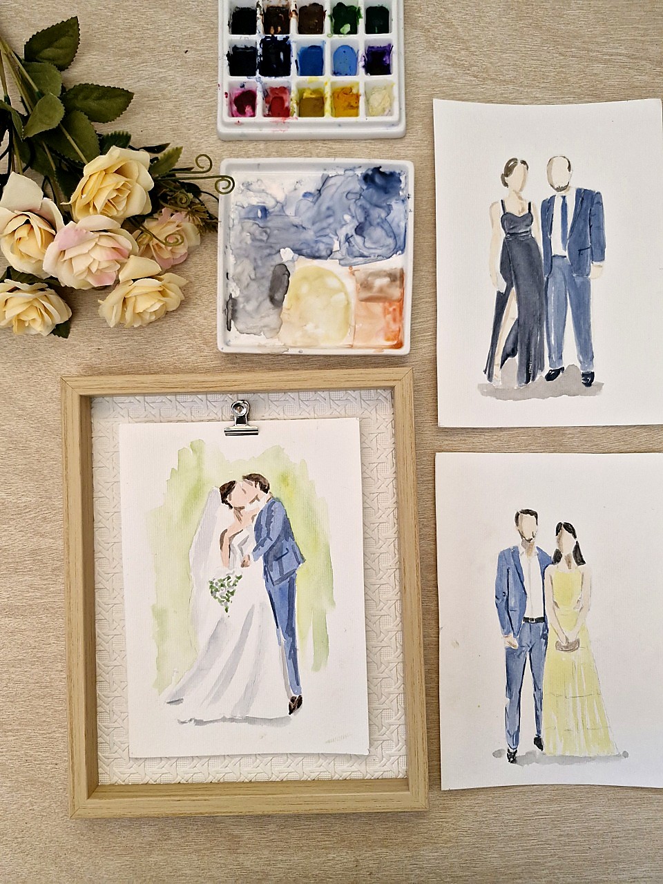 Aquarelas de casais e noivos em aquarela, com paleta de tintas e flores sobre mesa de madeira